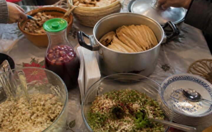 Mesa de cena navideña con tamales, ponche y platillos que llevaron los invitados